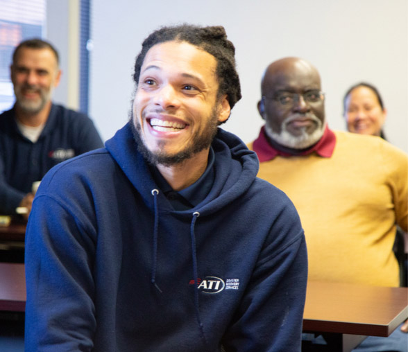 Man in ATI hoodie smiling at camera.
