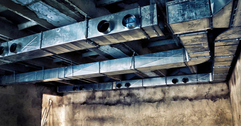 Metal ductwork installed in a rough, unfinished building.