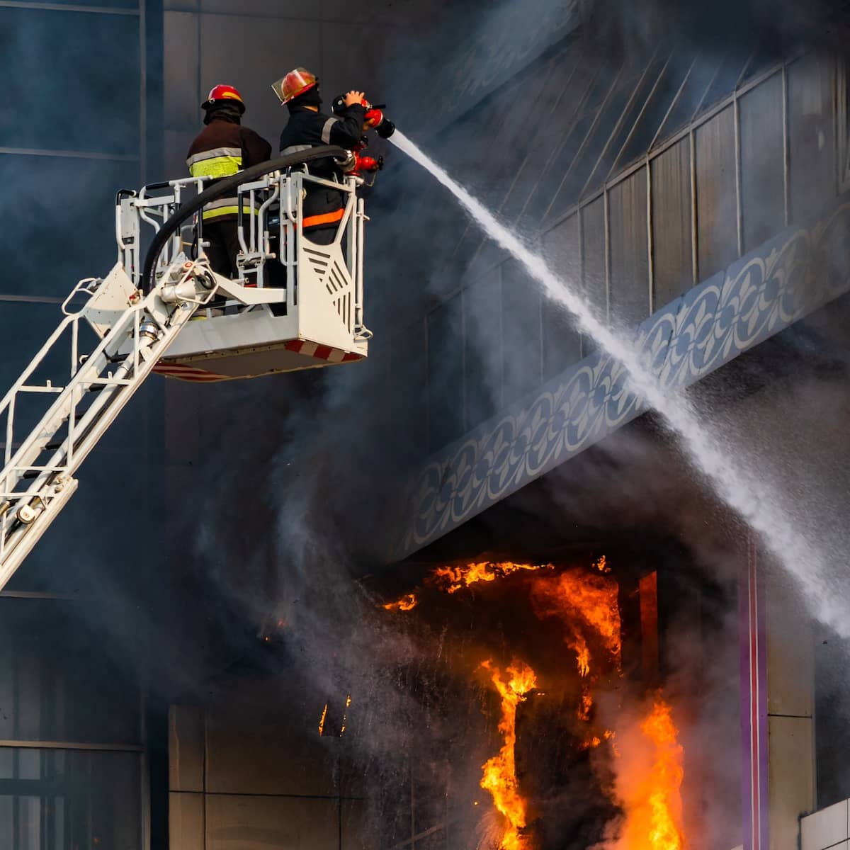 Firefighters on a bucket lift using water hoses to put out a fire at a commercial property | ATI Restoration