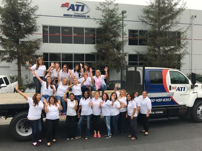 Group photo of American Technologies Inc. employees on a flatbed truck in front of their building.