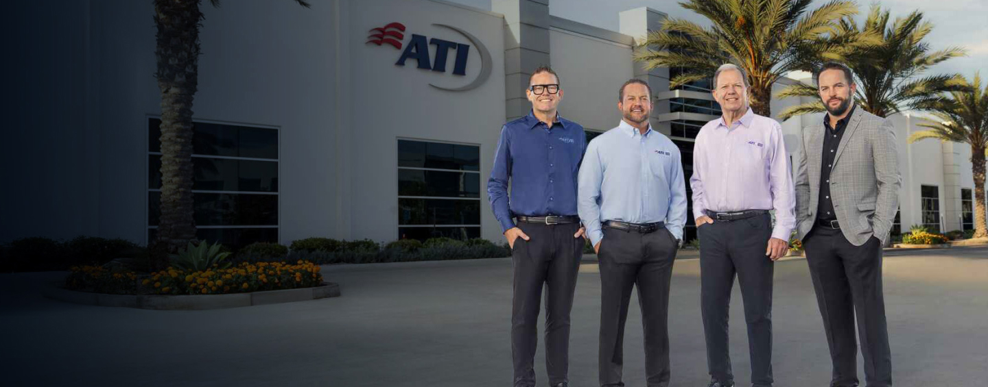 Four men in business casual attire stand in front of the ATI building.