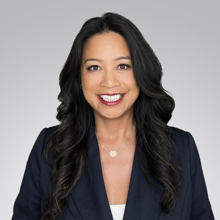 Headshot of a smiling woman with long dark hair wearing a dark blazer.