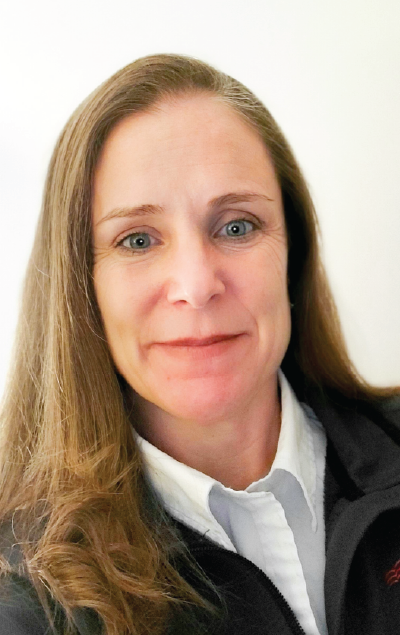 Headshot of a woman with long brown hair, wearing a dark jacket over a white collared shirt.