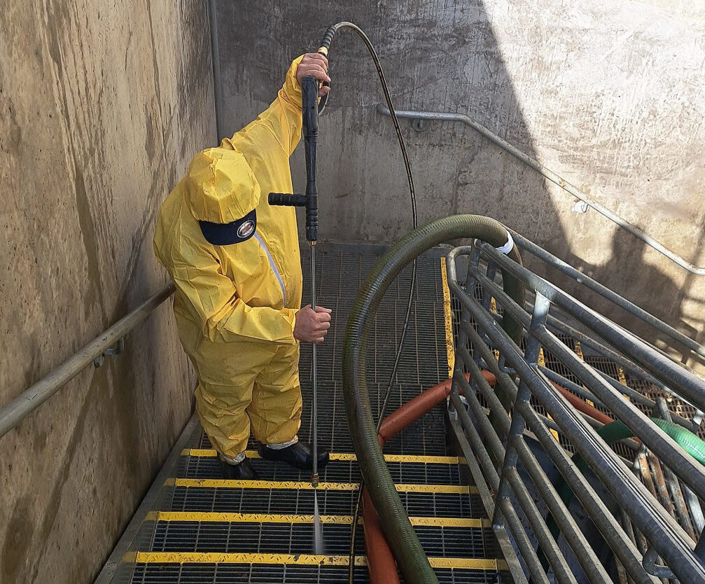 Person in yellow protective suit pressure washing a staircase.
